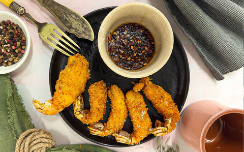 Crispy shredded coconut and panko coating 5 langoustine tails with their tails attached and a spicy sweet dip