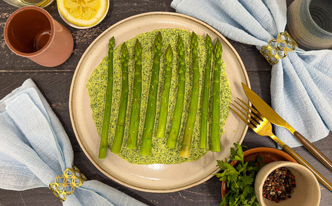 Bright green green goddess asparagus spears on a plate with a creamy herb sauce