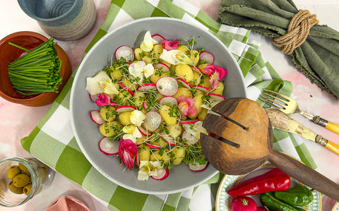 Bright edible flowers with white peeled Jersey Royals drizzled with truffle oil