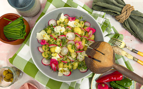 Bright edible flowers with white peeled Jersey Royals drizzled with truffle oil